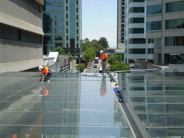 men cleaning glass roof and applying hydrophobic coating