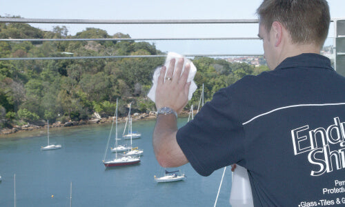 man cleaning glass railing to apply enduroshield